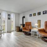 Two brown leather chairs, fireplace and wall art in a room with white brick walls.