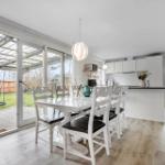 Dining area with table, chairs, and garden view. Kitchen with countertop and cabinets.