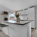 Modern kitchen with island, white cabinets, and view to the garden.