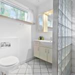 Badezimmer mit Toilette, Waschbecken und Dusche aus Glassteinen.