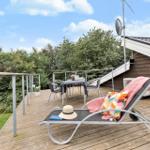 Terrasse mit Liegestuhl, Tisch und Stühlen, Blick auf Bäume und Himmel.
