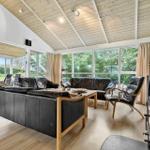 Wohnzimmer mit schwarzen Ledermöbeln, Holzboden und großem Fensterblick.