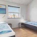 Zwei Betten mit blauen Decken, Fenster mit Pflanze und Wandbild.