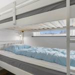 Doppelstockbett mit blauer Bettwäsche und kleinem Fenster.