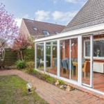 Terrasse mit Sitzgelegenheiten und Blick auf Garten mit blühendem Baum.