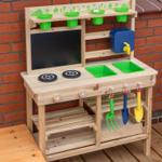 Holzspielküche mit grünen Becken und bunten Werkzeugen an der Wand.