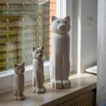 Drei weiße Katzenfiguren stehen auf einem Fensterbrett.