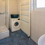 Badezimmer mit Dusche, Waschmaschine und Heizkörper