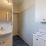 Badezimmer mit Waschbecken, Spiegel, Dusche und Handtüchern.