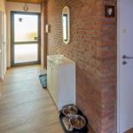 Flur mit Backsteinwand, weißem Schrank und Hundefutterstation