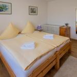 Ein Schlafzimmer mit Holzbett, zwei Nachttischen und einem Kinderbett.