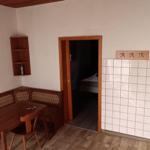 Essbereich mit Holztisch und Bänken. Tür führt in Schlafzimmer. Küchenwand mit Fliesen.