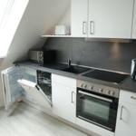 Küche mit Kühlschrank, Spülmaschine und Herd unter Dachschrägen.