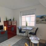 Wohnzimmer mit TV, Tisch, Stühlen und Wandbildern