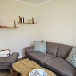 Ein Wohnzimmer mit Sofa, Kissen, Holztisch und Regalen an der Wand.