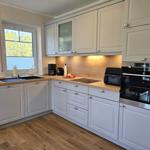 Küche mit hellen Schränken, Holzoberflächen und integriertem Backofen.