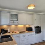 Küche mit hellen Schränken, Holzoberfläche und integriertem Ofen.