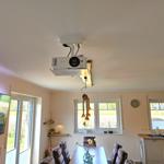 Raum mit Projektion, Essbereich und Küchenzeile. Fenster mit Blick auf Garten.