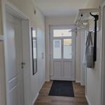 Flur mit Holzboden, Tür und Kleiderständer an der Wand