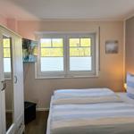 Schlafzimmer mit Doppelbett, Fenster und Kleiderschrank.