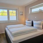 Schlafzimmer mit Bett, Fenstern und TV. Wandbild und Ankerdekoration.