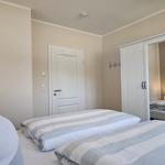 Schlafzimmer mit zwei Betten, Kleiderkabinett und Tür.