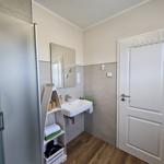 Badezimmer mit Dusche, Waschbecken und Spiegel. Holzdielenboden und graue Fliesen.