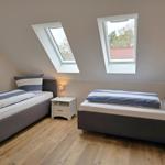 Zwei Einzelbetten mit blau-weißen Bettwäschen, Holzboden und zwei Dachfenster.