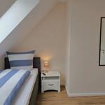 Schlafzimmer mit Dachschrägen, Bett, Nachttisch und Spiegel an der Wand.