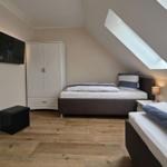 Zwei Betten, Schrank, TV und Dachschrägenfenster in einem Schlafzimmer.