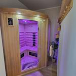 Innere eines Holzsaunas mit Glasfront und lila Beleuchtung.