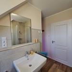 Badezimmer mit Dusche, Waschbecken und Spiegel unter Dachschräge