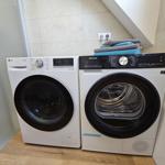 Waschmaschine und Trockner in einem Raum mit Holzboden und Wandbeleuchtung.