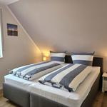 Schlafzimmer mit Doppelbett, Fenster und Nachttisch.