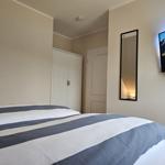 Schlafzimmer mit Bett, Kleiderschrank und Wandspiegel. Fernseher an der Wand.