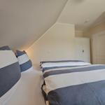 Schlafzimmer mit Doppelbett, Kleiderschrank und Spiegel an der Wand.