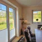 Essbereich mit Tisch, Stühlen und Blick auf Garten. Fenster und Tür mit Blick auf Grün.