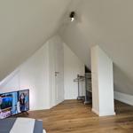 Schlafzimmer mit Dachschräge, Holzboden und Fernseher