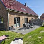 Haus mit Terrasse, Garten und Liegen. Tisch und Stühle stehen bereit.