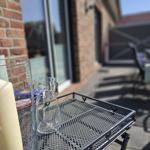 Außenbereich mit Tisch, Stühlen und Kerze auf Metalltablett.