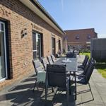 Terrasse mit Sitzgruppe und Garten. Hauswand aus Backstein. Hinterhof mit Zaun.