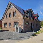 Zweistöckiges Haus mit Solaranlage und Dachgauben. Vorhof mit Pflastersteinen und Satellitenschüsseln.