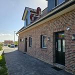 Haus mit Backsteinfassade, Eingangstür und Satellitenschüsseln auf dem Dach.