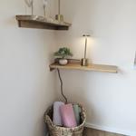 Ecke mit Holzregalen, Lampen und Korb mit Handtüchern.