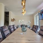 Esszimmer mit langem Holztisch, Stühlen und Fernseher an der Wand.