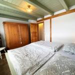 Schlafzimmer mit Doppelbett, Holzschrank und Deckenbalken.