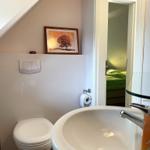 Badezimmer mit Waschbecken, Toilette und Bild an der Wand