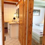 Badezimmer mit Waschbecken und Spiegel. Nebenraum mit Bett und Wandbild.