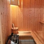 Sauna mit Holzbank, Eimer und Steinkasten.