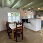 Essbereich mit Tisch, Stühlen und Kücheninsel mit Barhockern.